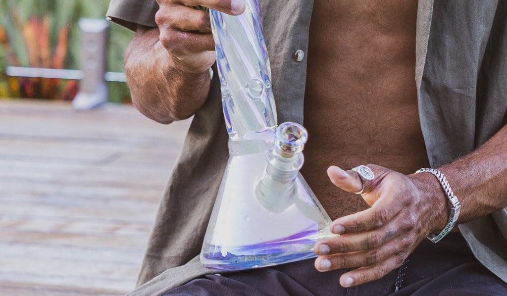 A man holding a large glass beaker bong