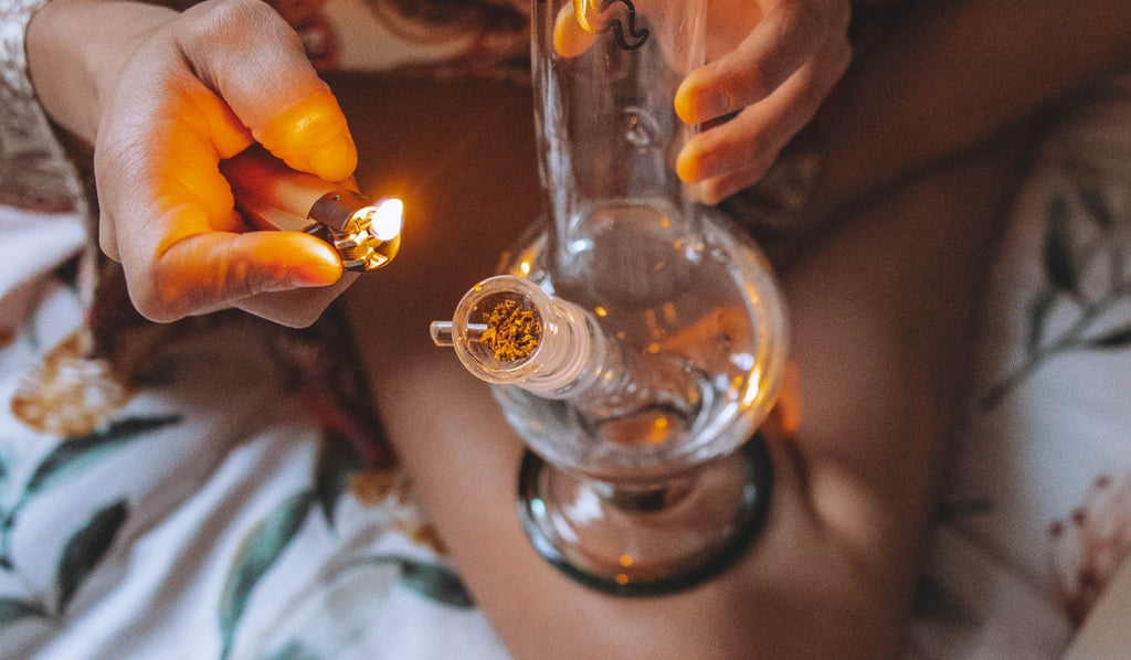 A person lighting a bowl filled with dried cannabis