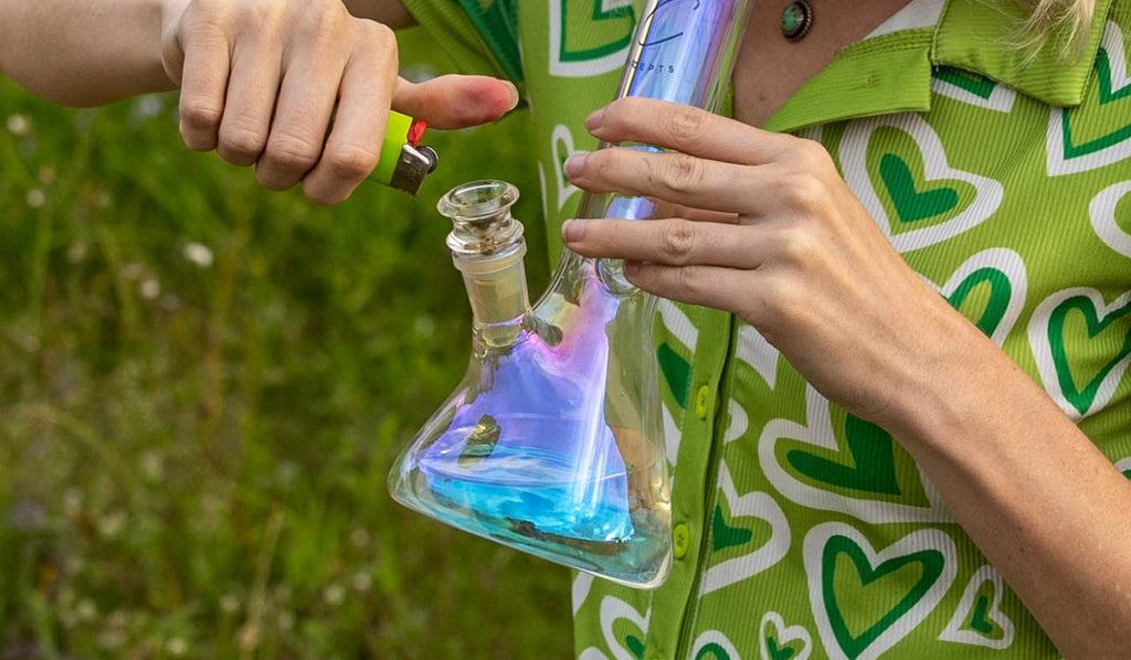 A person lighting a glass beaker bong