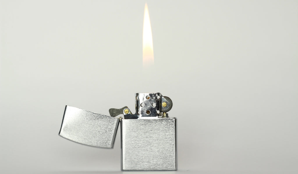 A silver Zippo lighter open and lit