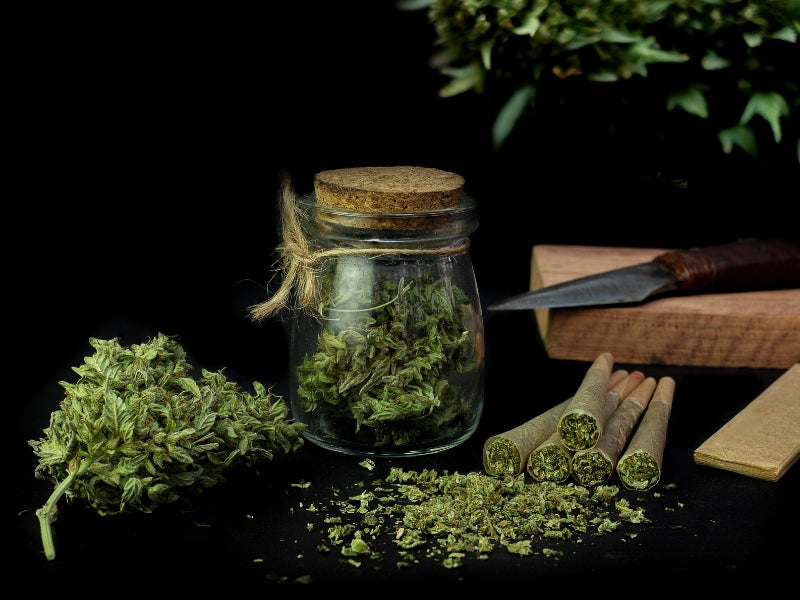 Cannabis In A Glass Jar Alongside Joints