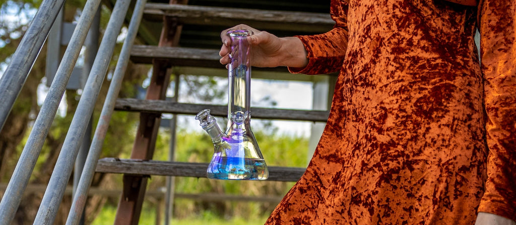Person holding glass bong with bong water inside