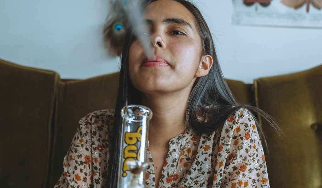 Woman exhaling after smoking from a glass bong