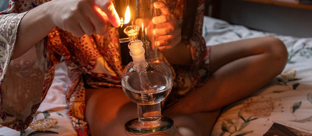 Woman lighting glass round base bong