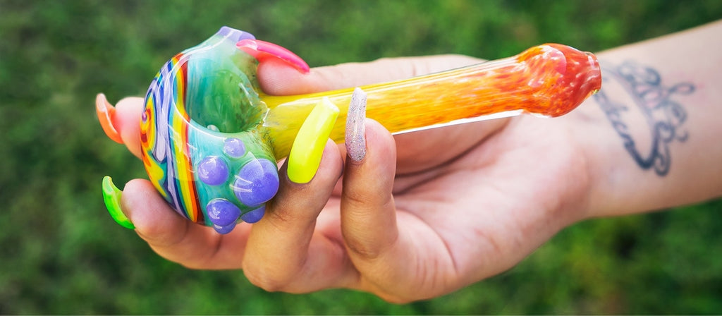 A hand holding a colourful GRAV glass spoon pipe