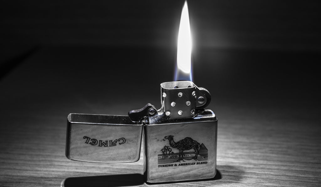A lit silver Zippo lighter on a table
