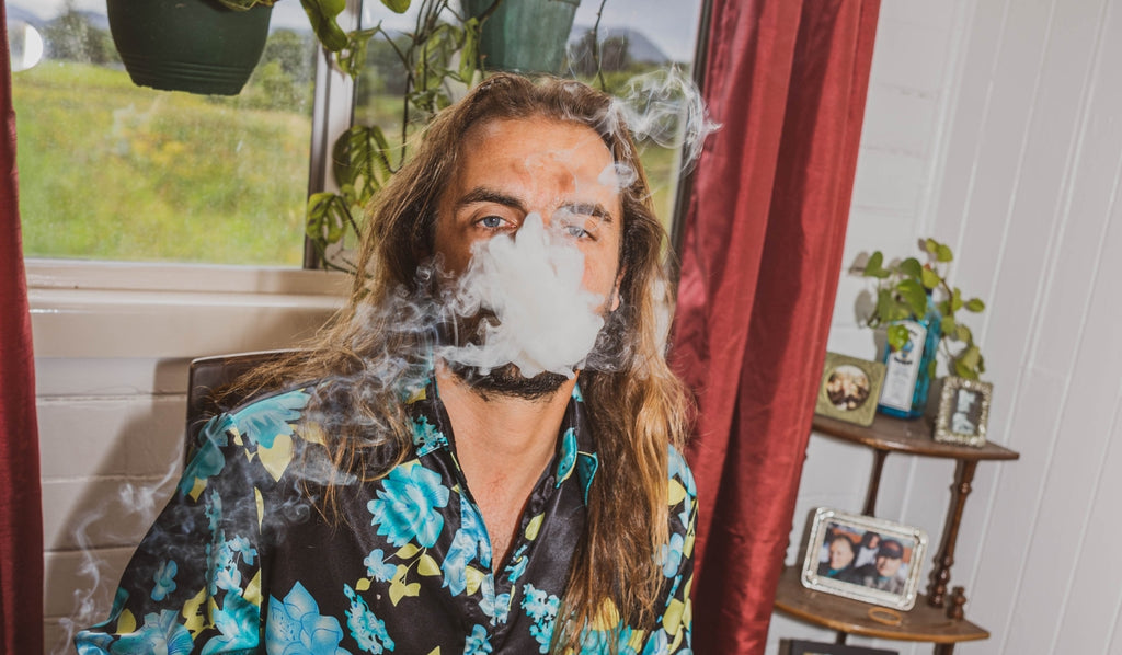 A man exhaling cannabis smoke at a table
