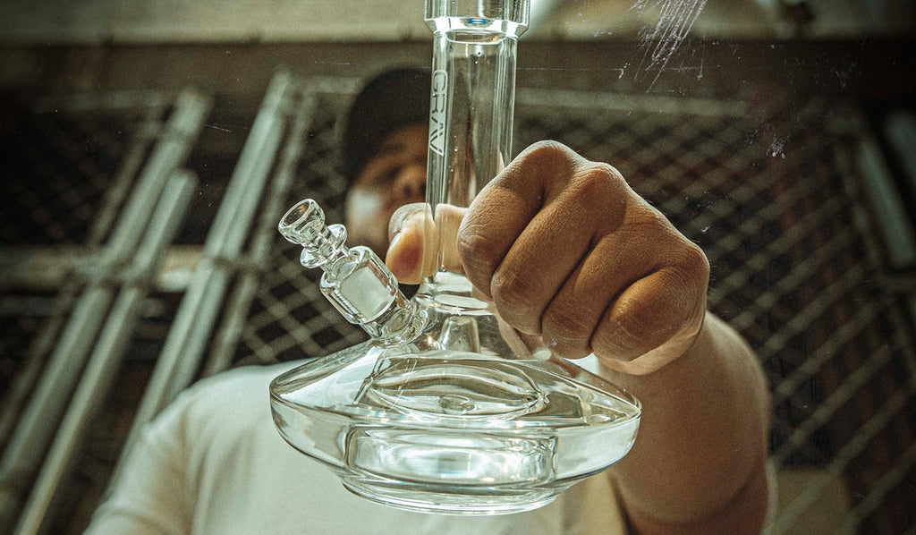 A man holding a glass percolator bong