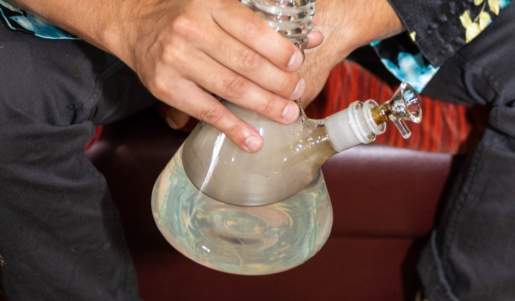 A person holding a beaker glass bong