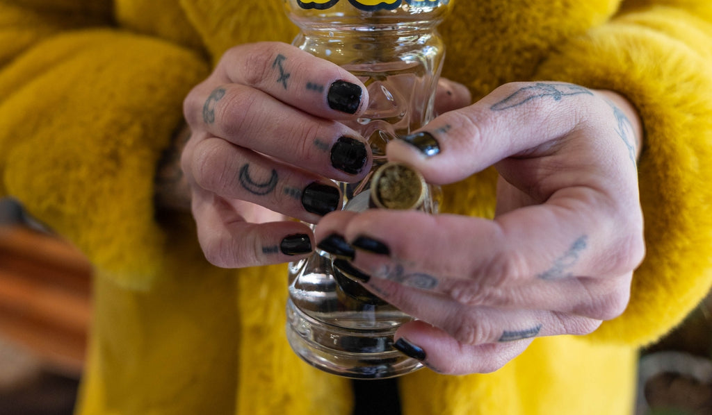 A person holding a metal bowl filled with cannabis