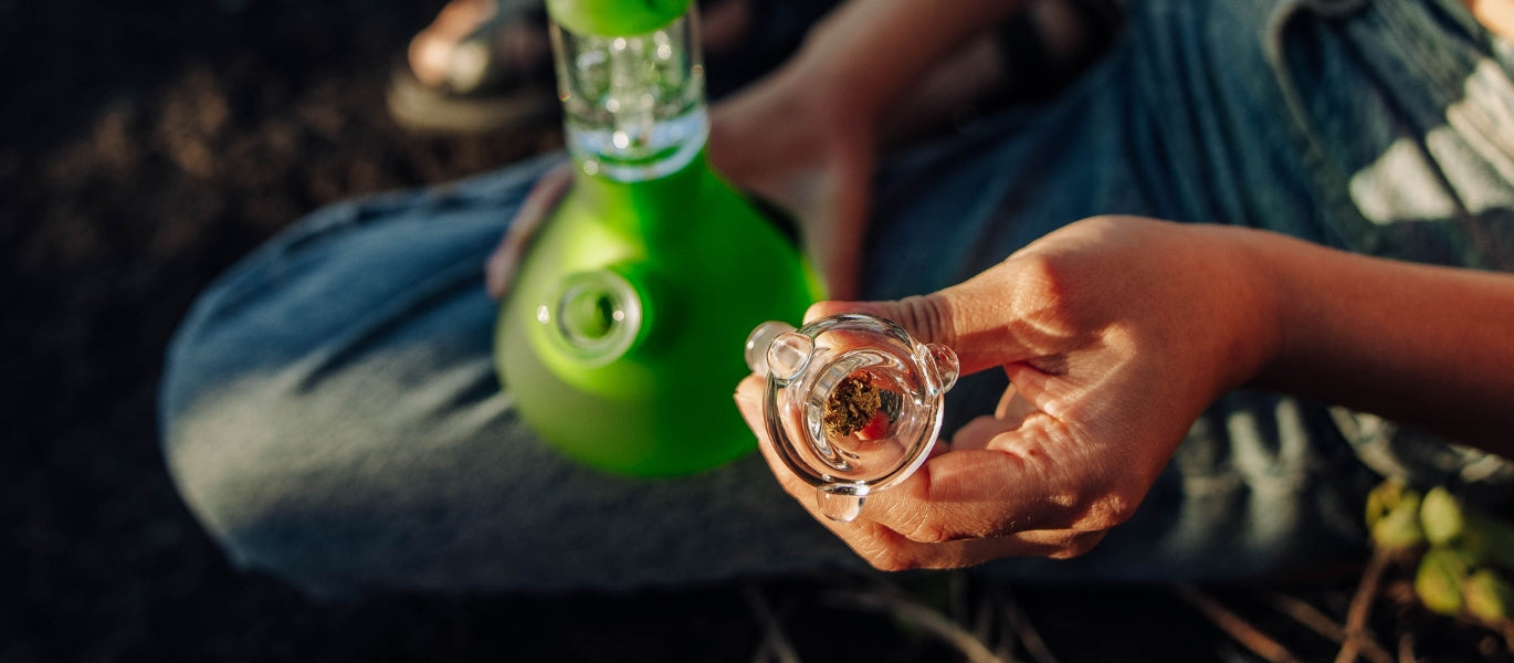 A person inserting a cone piece into a glass bong