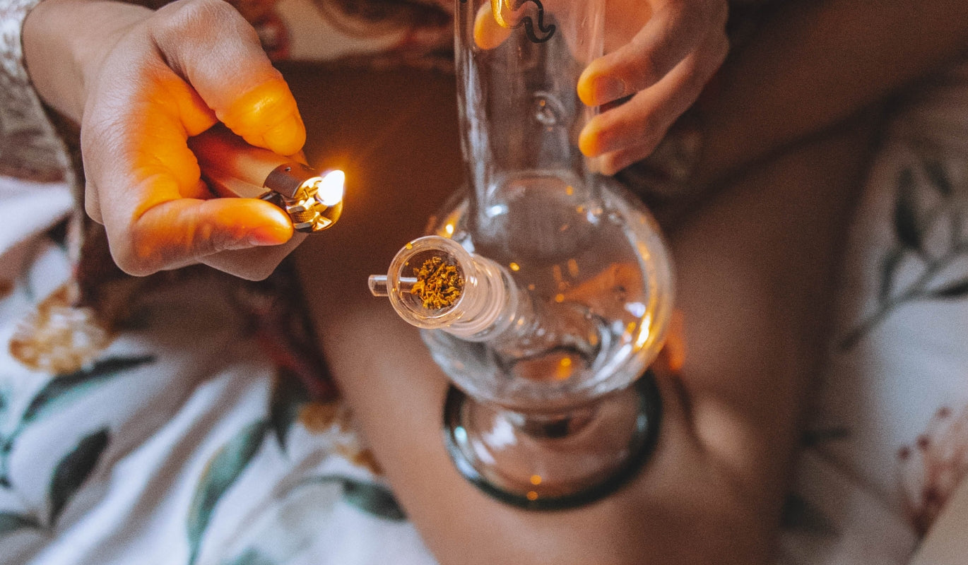 A person lighting a bowl filled with dried cannabis