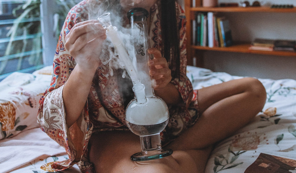 A woman inhaling from a bubble glass bong