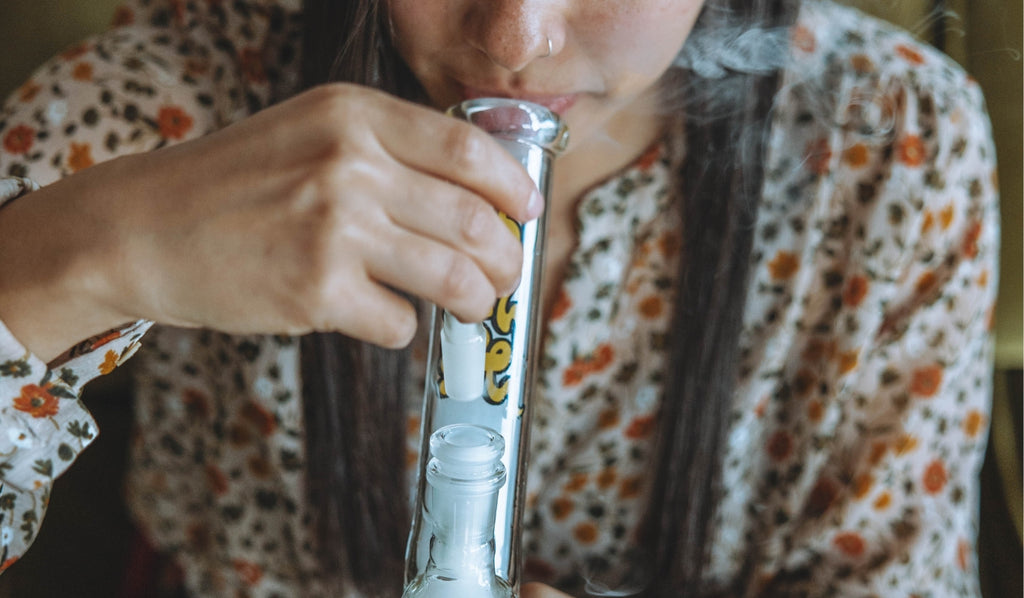 A woman inhaling from a gripper glass bong
