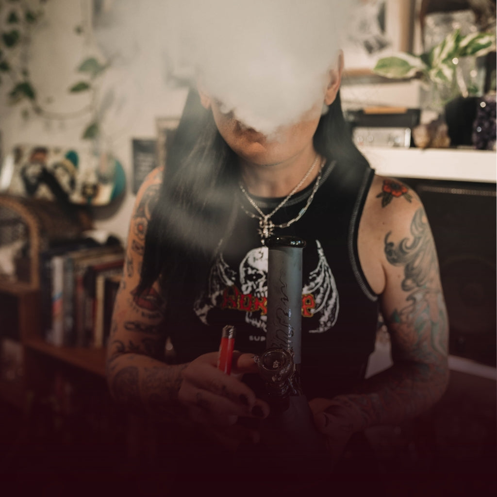 Woman exhaling smoke from a glass bong