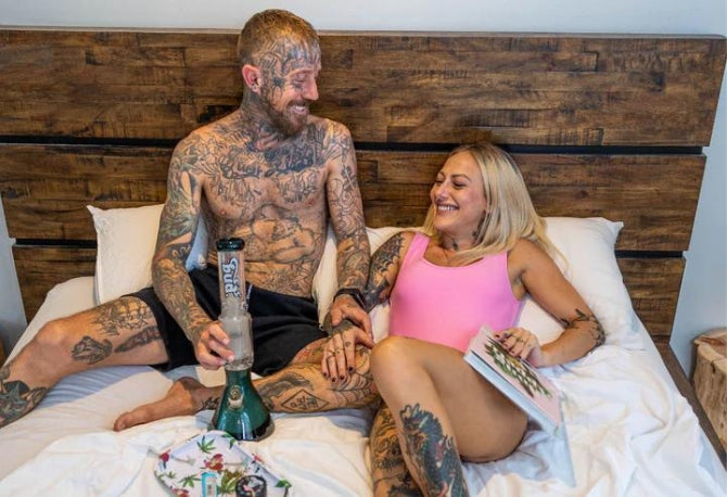 Man and woman laying on a bed with a Bud Matrix Percolator Bong