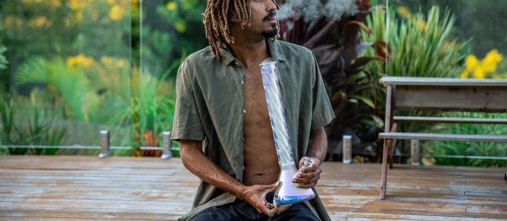 Man exhaling from a large glass bong