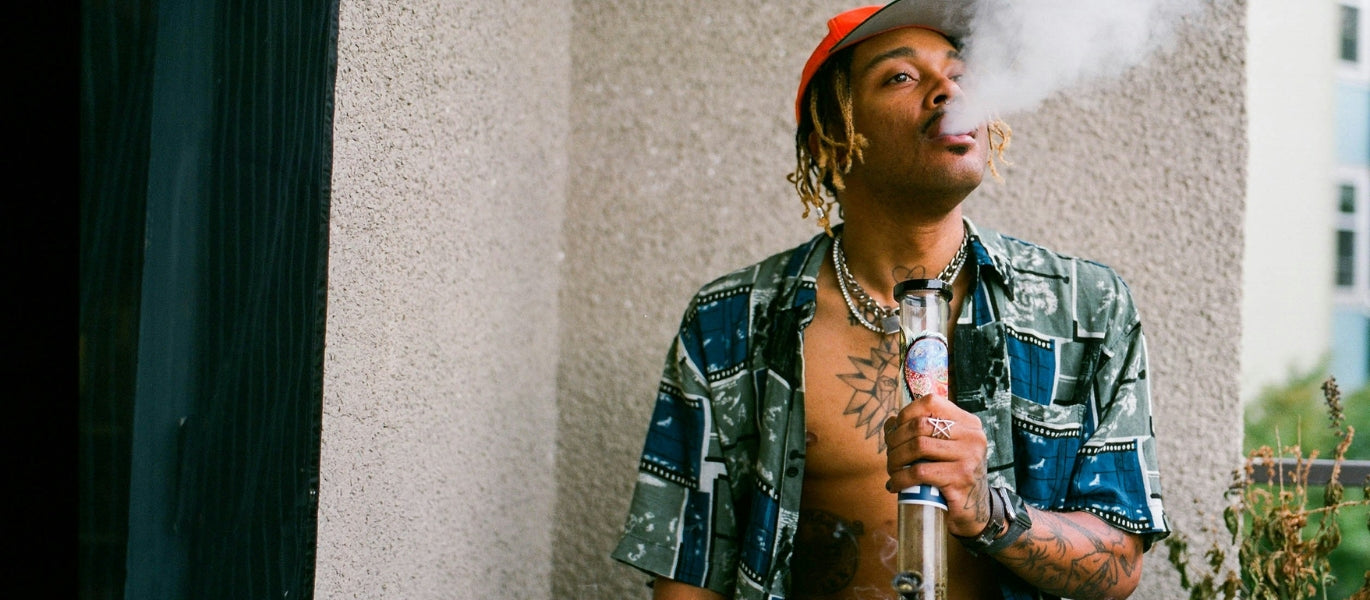 Man exhaling from a large glass bong