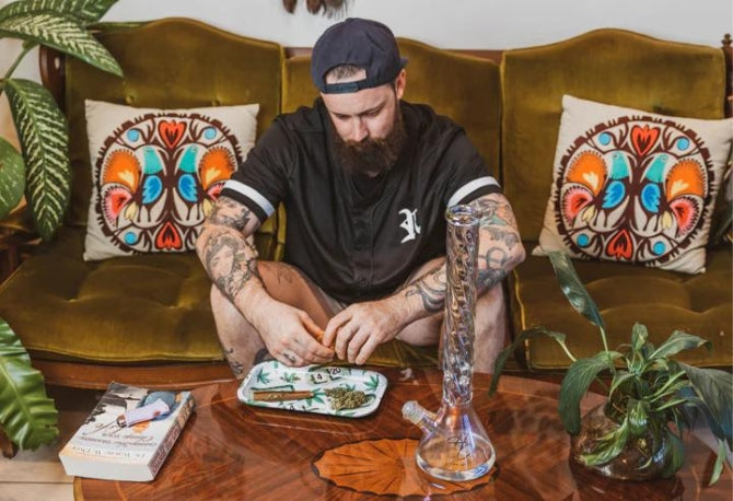 Man on couch preparing a glass bong