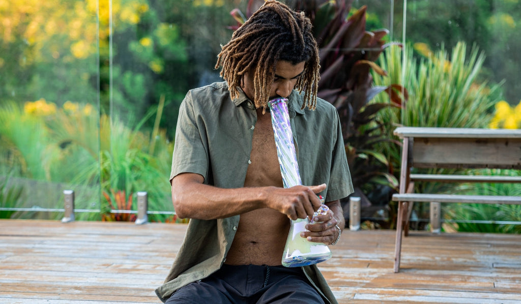 Man sitting and smoking from a large glass bong