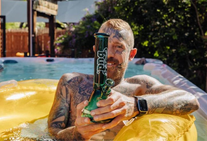 Man in a pool holding a Bud Beaker Bong - Teal
