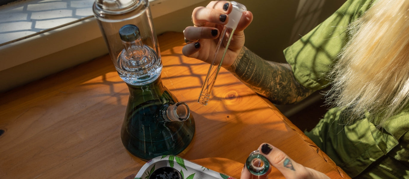 Person holding a downstem next to a bong
