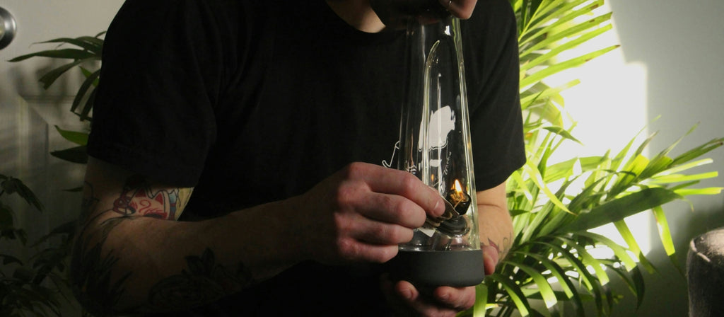 Person lighting a glass bong with hemp wick