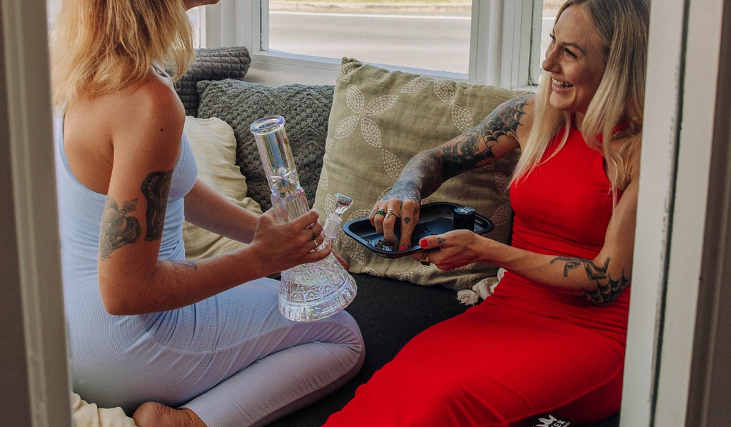 Two women preparing a bong with cannabis
