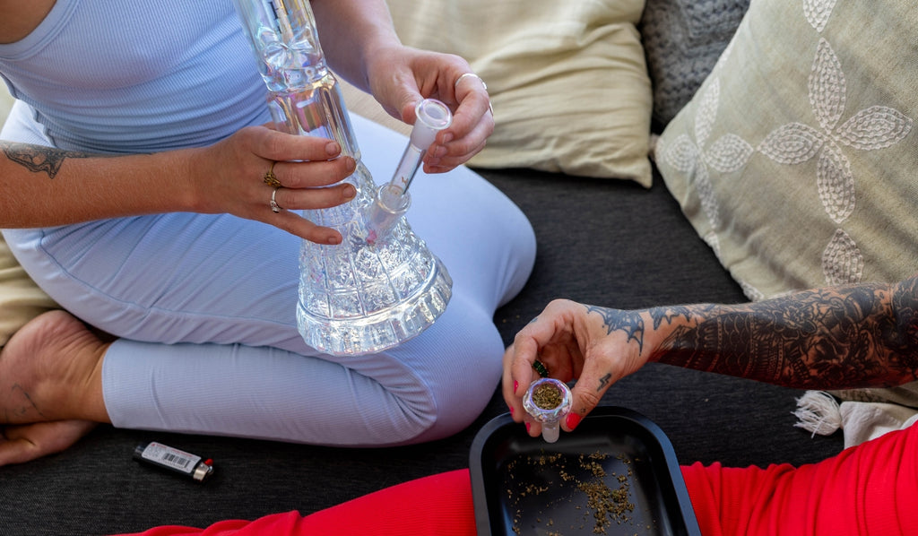 Two women preparing a bowl with cannabis