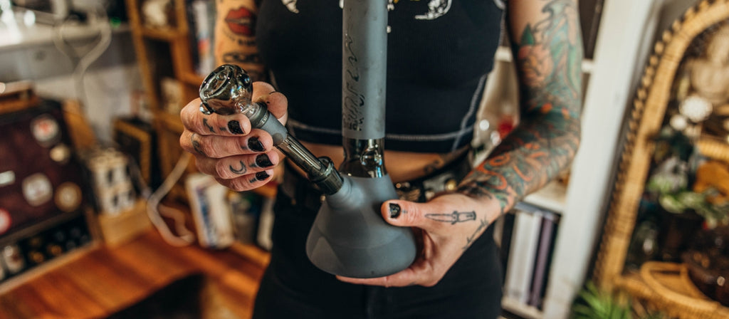 Woman inserting downstem into matte black glass bong