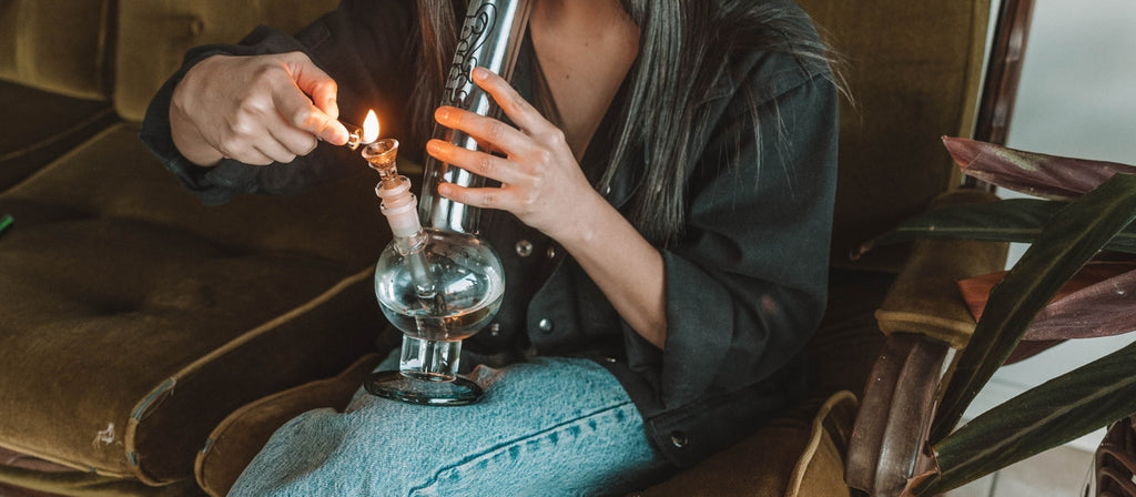 Woman lighting glass cone piece in bong