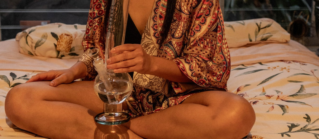 Woman sitting holding glass round base bong