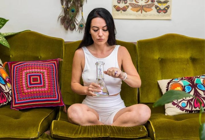 Woman on couch smoking a Higher Concepts glass bong